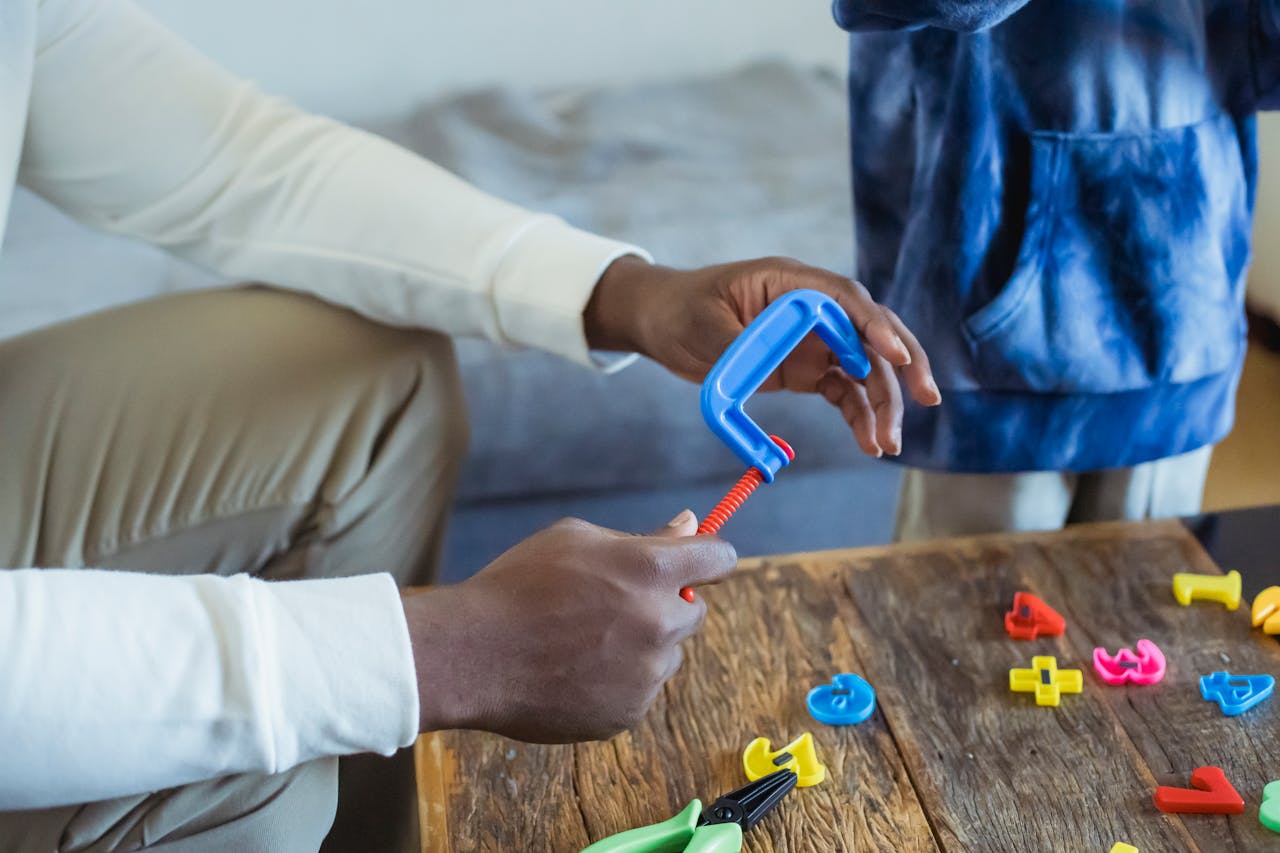 who-we-are High angle of crop anonymous dad playing with toy instrument while spending time with son